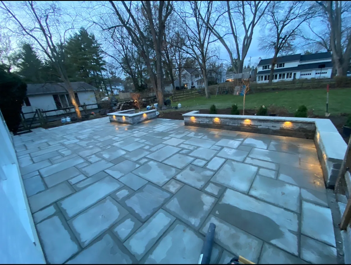 Illuminated natural-stone patio completed by Queen City Hardscapes